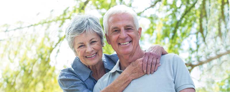 Senior couple smiling and hugging outdoors